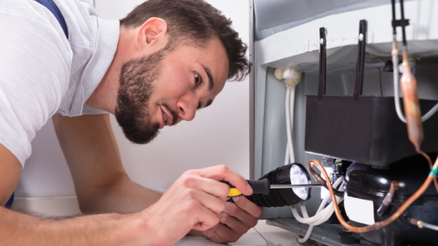 Un frigo en panne, en train d'être réparé.